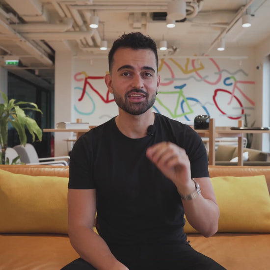 Man presenting AdCreative.ai Ad Creator - Custom Platform (Freemium) Business AI in a modern office with colorful branding and casual seating. Ideal for showcasing AI-powered ad software in a business environment.