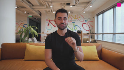 Man presenting AdCreative.ai Ad Creator - Custom Platform (Freemium) Business AI in a modern office with colorful branding and casual seating. Ideal for showcasing AI-powered ad software in a business environment.